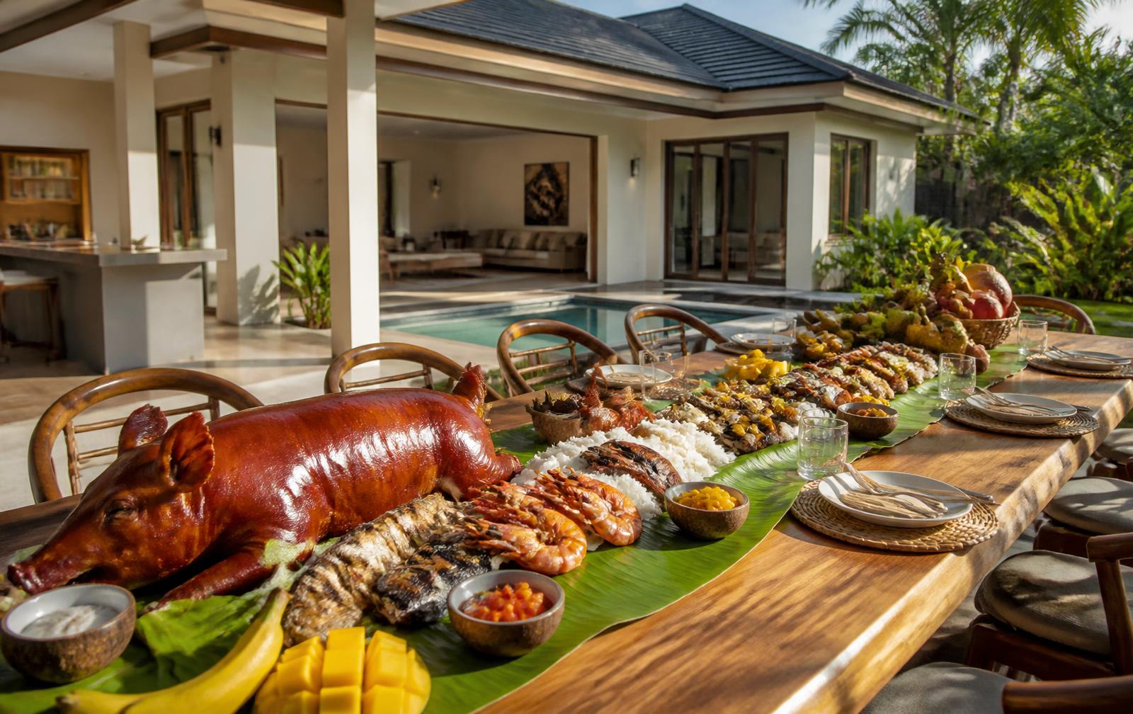 Long Filipino feast table beside a Uwina villa with lechon, seafood and rice